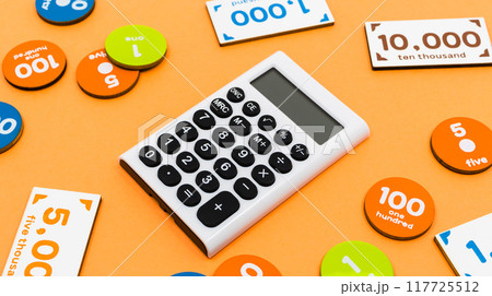 オレンジ色の背景に計算機とおもちゃのお金 出費や支払いのイメージ素材 オレンジ色の背景に計算機とおもちゃのお金 出費や支払いのイメージ素材 117725512