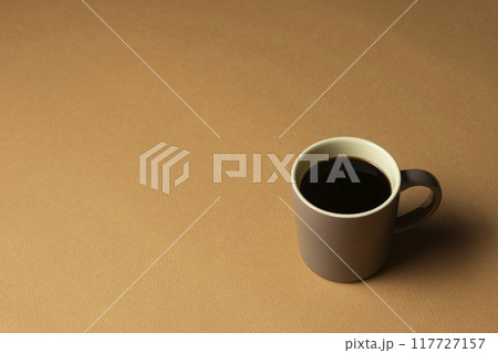 茶色の背景に置いたコーヒーカップ 117727157
