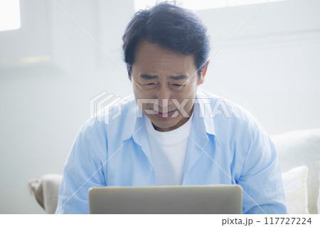 リビングでノートパソコンを使うミドル男性 リビングでノートパソコンを使うミドル男性 117727224