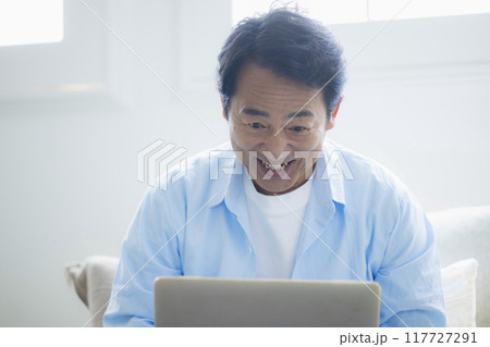 リビングでノートパソコンを使うミドル男性 117727291