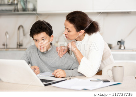 Mother helps her teenage son do schoolwork, solve problems together and find answers Mother helps her teenage son do schoolwork, solve problems together and find answers 117727739