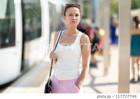 Adult woman standing at train station 117727749