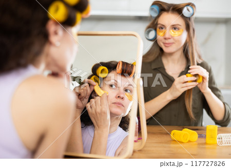 Two women curl their hair with curlers and use patches Two women curl their hair with curlers and use patches 117727826
