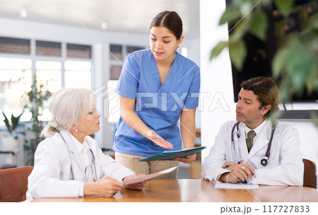 Young female physician discussing diagnosis of patients with colleagues Young female physician discussing diagnosis of patients with colleagues 117727833