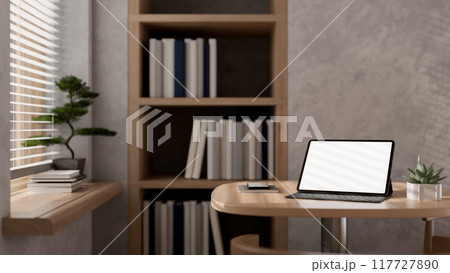 A digital tablet mockup and a wireless keyboard on a wooden table in a modern loft office. 117727890