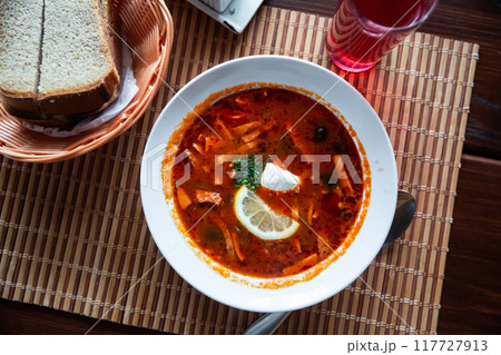 Traditional Russian meat soup Solyanka with sour cream and lemon 117727913