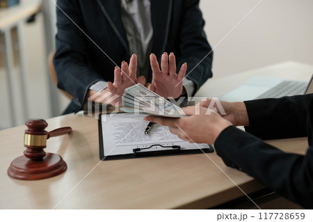 Two people are sitting at a desk with a judge's gavel on the table Two people are sitting at a desk with a judge's gavel on the table 117728659