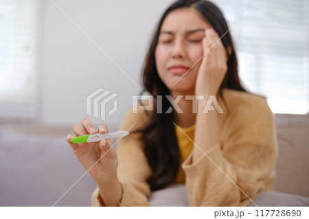 A woman is holding a pregnancy test and looking at it 117728690