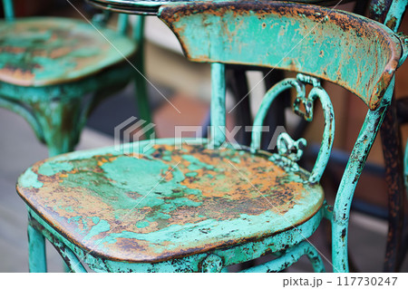 Refinished metal chair showing signs of wear and corrosion in a cafe setting 117730247