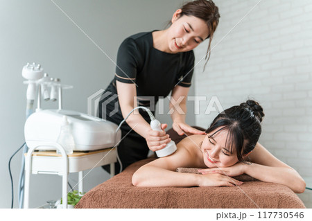 エステサロンでマシンを使うエステティシャン・セラピスト・スタッフと女性 117730546