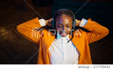 Young pupil relaxing with modern music on headphones, sitting laid back and taking a break from writing an essay. Student finishes tasks, engaging in mindfulness activities through songs. Camera B. Young pupil relaxing with modern music on headphones, sitting laid back and taking a break from writing an essay. Student finishes tasks, engaging in mindfulness activities through songs. Camera B. 117730832
