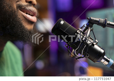 Songwriter musician composing a new track and recording it on microphone, singing aloud in his home studio and editing. Producer performing a song, acoustical engineering. Close up. Songwriter musician composing a new track and recording it on microphone, singing aloud in his home studio and editing. Producer performing a song, acoustical engineering. Close up. 117731047