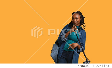 African american woman holding microphone, performing songs in concert and dancing, studio background. Energetic musician singing to spectators, doing karaoke, having fun, camera B 117731123