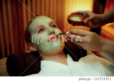 Woman indulges in rejuvenating with luxurious face cream spa massage. Quiescent 117731971