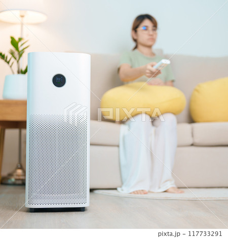 Air Purifier with woman relax on sofa. Purification system for filter and cleaning dust PM2.5 HEPA and virus in home. Allergy, Pure air, health, Wellness lifestyle and Air Pollution 117733291