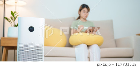 Air Purifier with woman relax and use tablet on sofa. Purification system for filter and cleaning dust PM2.5 HEPA and virus in home. Allergy, Pure air, health, Wellness lifestyle and Air Pollution Air Purifier with woman relax and use tablet on sofa. Purification system for filter and cleaning dust PM2.5 HEPA and virus in home. Allergy, Pure air, health, Wellness lifestyle and Air Pollution 117733318