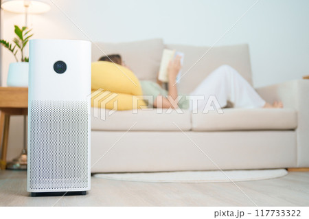 Air Purifier with woman read and relax on sofa. Purification system for filter and cleaning dust PM2.5 HEPA and virus in home. Allergy, Pure air, health lifestyle, Wellness life and Air Pollution Air Purifier with woman read and relax on sofa. Purification system for filter and cleaning dust PM2.5 HEPA and virus in home. Allergy, Pure air, health lifestyle, Wellness life and Air Pollution 117733322