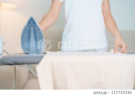 Woman hold Electric hot iron press T shirt clothes on ironing board, Intelligent automatic steam iron. Laundry, Housework, Housekeeping, Domestic hygiene, household of chores and daily routine concept Woman hold Electric hot iron press T shirt clothes on ironing board, Intelligent automatic steam iron. Laundry, Housework, Housekeeping, Domestic hygiene, household of chores and daily routine concept 117733336