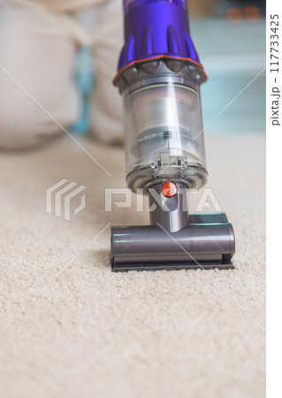 Woman cleaning Carpet with cordless Vacuum cleaner. Housewife using wireless Vacuum for big cleaning home. Housework, Housecleaning, Housekeeping, Removes dust, Domestic hygiene and daily routine 117733425
