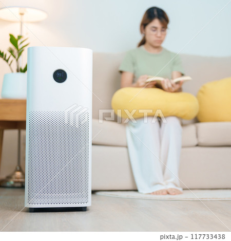 Air Purifier with woman read and relax on sofa. Purification system for filter and cleaning dust PM2.5 HEPA and virus in home. Allergy, Pure air, health lifestyle, Wellness life and Air Pollution 117733438