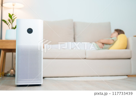 Air Purifier with woman relax and sleep on sofa. Purification system for filter and cleaning dust PM2.5 HEPA and virus in home. Allergy, Pure air, health, Wellness lifestyle and Air Pollution 117733439