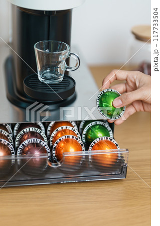 hand making Espresso Coffee by Coffee Maker Machine with Capsule of roasted coffee bean on wood table bar. Daily beverage drink at Home, Apartment and Office concept 117733504