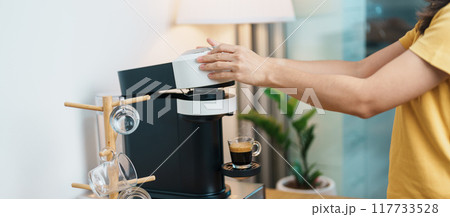 hand making Espresso Coffee by Coffee Maker Machine with Capsule of roasted coffee bean on wood table bar. Daily beverage drink at Home, Apartment and Office concept hand making Espresso Coffee by Coffee Maker Machine with Capsule of roasted coffee bean on wood table bar. Daily beverage drink at Home, Apartment and Office concept 117733528