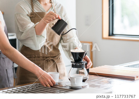 カフェ・コーヒーショップ・喫茶店でコーヒーを淹れるバリスタ・焙煎士の女性スタッフ・マスター 117733767