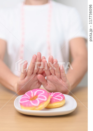woman hand reject donut dessert, female refuse Unhealthy junk food. Dieting control, Weight loss, Obesity, eating lifestyle and nutrition concepts woman hand reject donut dessert, female refuse Unhealthy junk food. Dieting control, Weight loss, Obesity, eating lifestyle and nutrition concepts 117736096