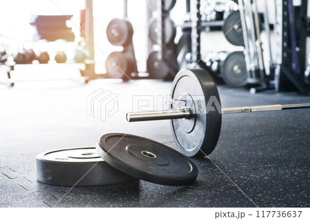 Rows of metal barbells on floor and rack for strength training in gym. 117736637