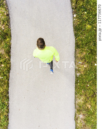 Aerial view of a runner running through autumn park on jogging path. Morning running training. Aerial view of a runner running through autumn park on jogging path. Morning running training. 117736670