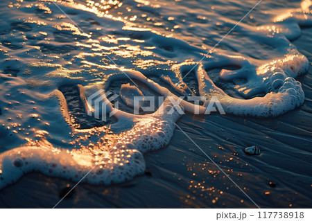 Close-up of word love written in sand, with waves washing over it and warm sunlight creating a golden glow and soft reflections, emphasizing romantic feel and tranquility 117738918