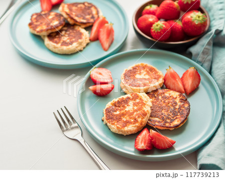 Sweet cheese pancakes on plate served strawberries. Cottage cheese pancakes, syrniki, ricotta fritters, curd fritters, Copy space for text or design. 117739213