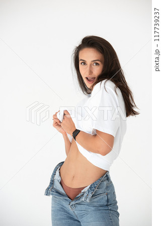 Happy beautiful girl posing in a new hot summer look. Wearing blue jeans and white t-shirt 117739237