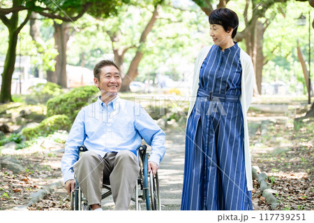 車椅子で公園を散歩するシニア夫婦 車椅子で公園を散歩するシニア夫婦 117739251