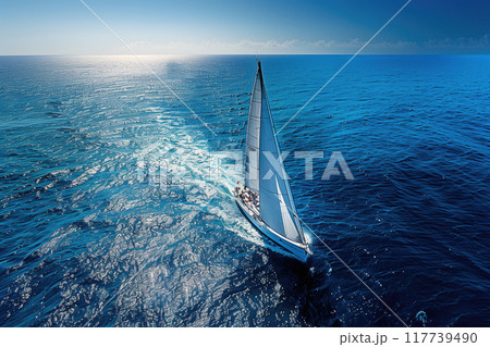 Sailboat gliding through open ocean with clear skies and calm waters creating a peaceful and serene setting and evoking feelings of freedom and adventure 117739490