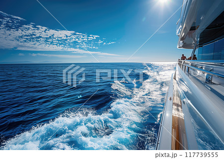 Cruising on a luxurious yacht with clear blue water and sunny skies casting reflections Relaxing on deck while enjoying picturesque seascape and distant horizons 117739555