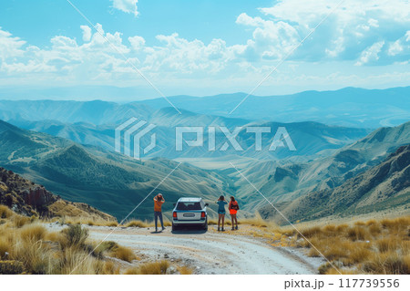 Group of people standing near parked SUV, admiring breathtaking mountain range in the distance. Picture captures essence of adventure, serenity, and natural beauty 117739556