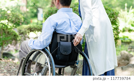 車椅子で公園を散歩するシニア夫婦　後ろ姿 117739784