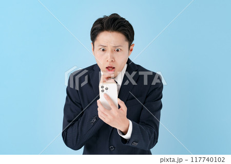 スマホを持って驚くビジネスマン 117740102
