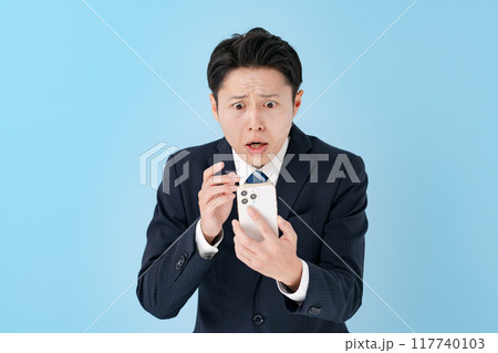 スマホを持って驚くビジネスマン 117740103