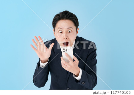 スマホを持って驚くビジネスマン 117740106
