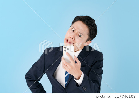 スマホを持って驚くビジネスマン スマホを持って驚くビジネスマン 117740108