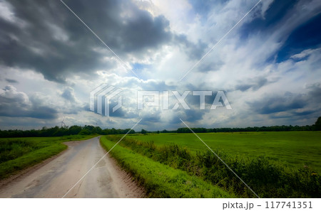 A stunning and scenic country road stretching under the vast and dramatic clouds above A stunning and scenic country road stretching under the vast and dramatic clouds above 117741351