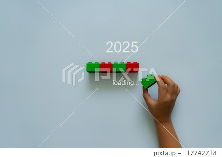 Loading new year 2024 to 2025 with child hand putting plastic block in progress bar. Loading new year 2024 to 2025 with child hand putting plastic block in progress bar. 117742718