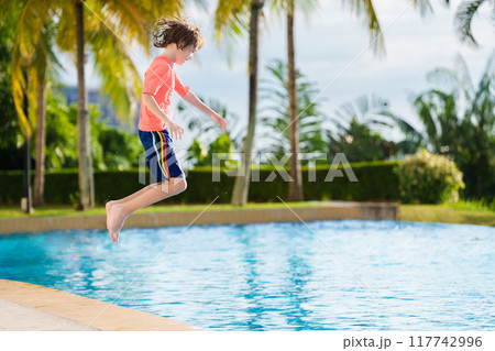 Kids jump into swimming pool. Summer water fun. 117742996