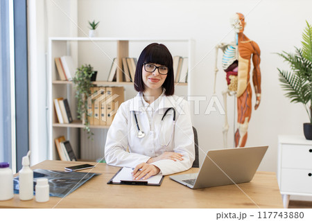 Confident female doctor at office desk ready to assist patients 117743880