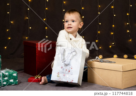 Little two-year-old boy opens Christmas gifts at home 117744818