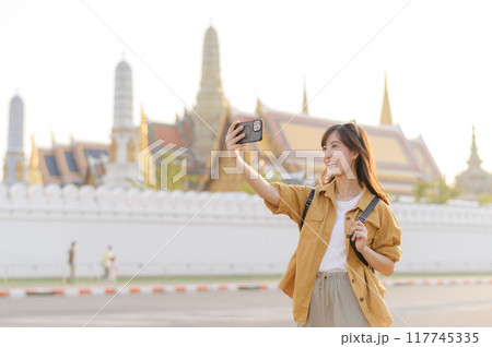 Traveler asian woman in her 30s explores the Grand Palace with a local guide. Uncover hidden gems and immerse yourself in Thai culture with her adventure. 117745335