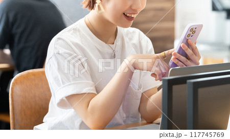 笑顔でスマホを使う若い日本人ビジネスウーマン 笑顔でスマホを使う若い日本人ビジネスウーマン 117745769